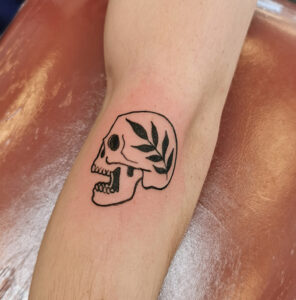 Tatuering av döskalle och lagerkrans.