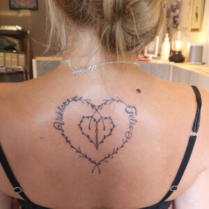 Hjärtformad tatuering i flora och namn.