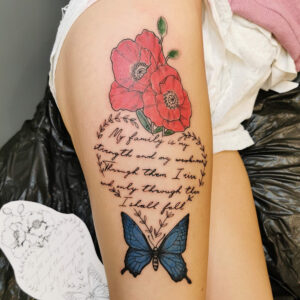Tatuering av fjäril, blommster och text.