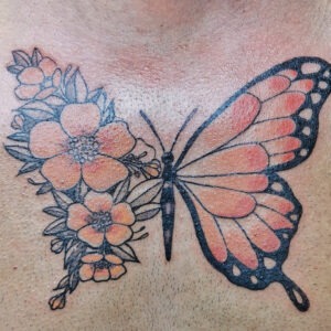 Tatuering av fjärill som övergår till blommster.